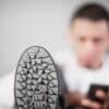 Selective Focus Photography of Man Sitting Beside Wall With Gray Sneaker