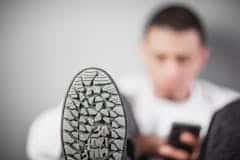 Selective Focus Photography of Man Sitting Beside Wall With Gray Sneaker
