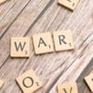 Scrabble letters spelling war on a wooden table