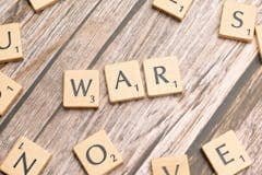 Scrabble letters spelling war on a wooden table