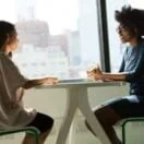 two women sitting beside table and talking about therapy