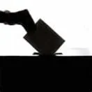 a person is casting a vote into an election box